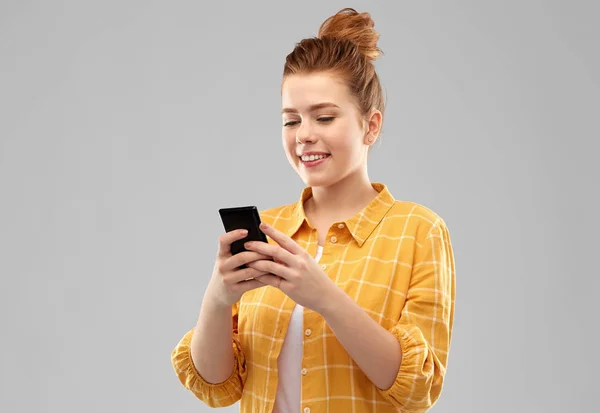 Sorrindo menina adolescente de cabelos vermelhos usando smartphone — Fotografia de Stock