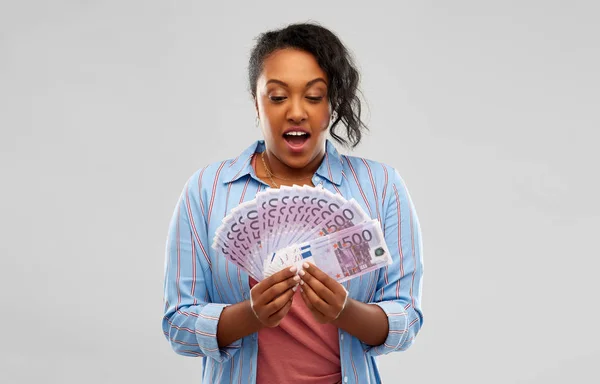 Mujer afroamericana sorprendida con dinero en euros — Foto de Stock