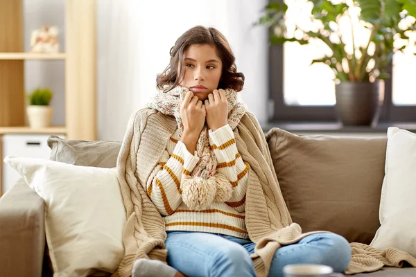 Sad sick woman in blanket and scarf at home — Stock Photo, Image