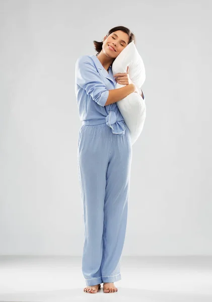 Feliz jovem mulher em azul pijama abraçando travesseiro — Fotografia de Stock