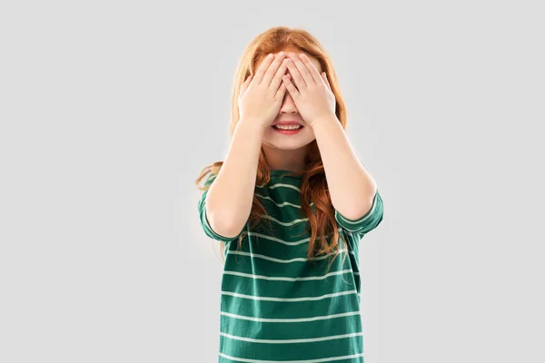 Glimlachend roodharige meisje met ogen gesloten door handen — Stockfoto