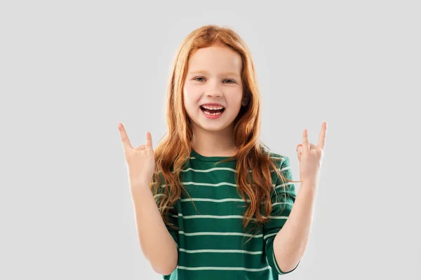 Улыбающаяся рыжеволосая девушка с жестом рока — стоковое фото