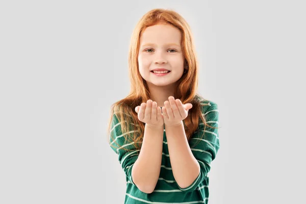 Usmívající se rudovlasá dívka držící něco na dlaních — Stock fotografie