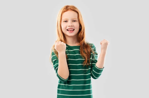 Usmívající se rudovlasá dívka oslavující úspěch — Stock fotografie