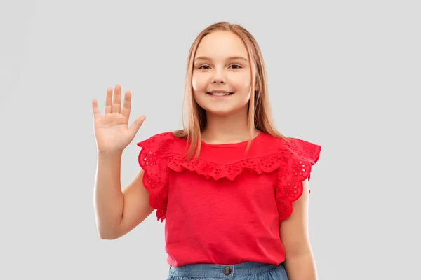 Mooi glimlachend meisje in rood shirt zwaaiende hand — Stockfoto