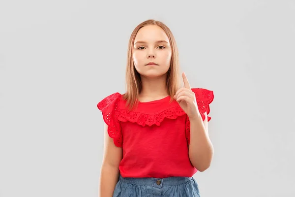 Chica seria en camisa roja señalando el dedo hacia arriba —  Fotos de Stock