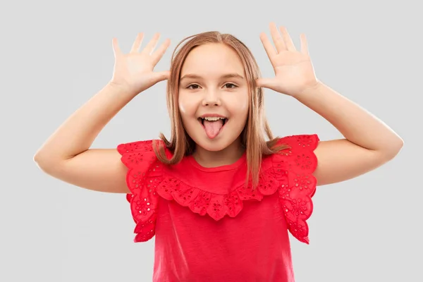 Funny girl showing her tongue and making big ears — Stock Photo, Image