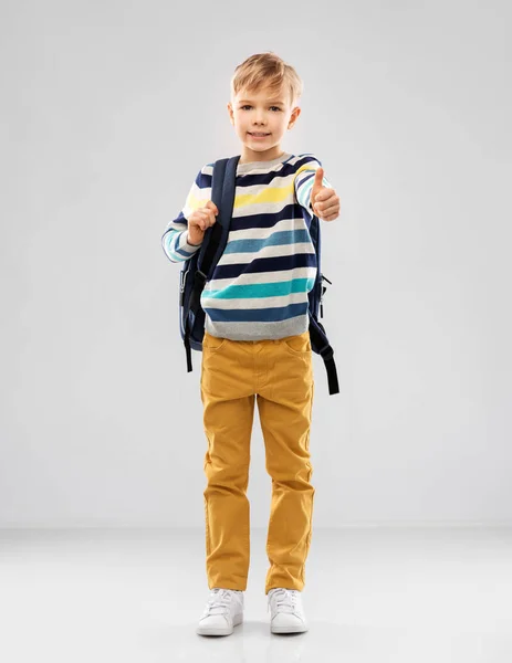 Student chłopiec z torbą szkoły pokazując kciuki w górę — Zdjęcie stockowe