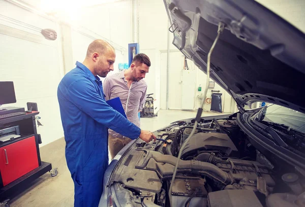 Automechaniker mit Klemmbrett und Mann im Autohaus — Stockfoto