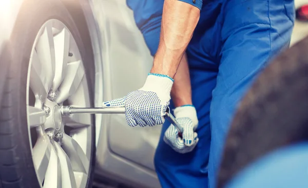 Mecânico com chave de fenda trocando pneu do carro — Fotografia de Stock