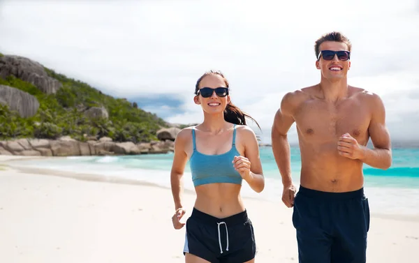 Par i sportkläder som löper längs på stranden — Stockfoto