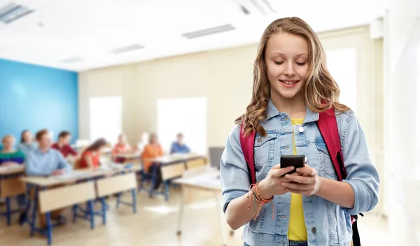 Adolescente estudiante chica con la escuela bolsa y teléfono inteligente — Foto de Stock