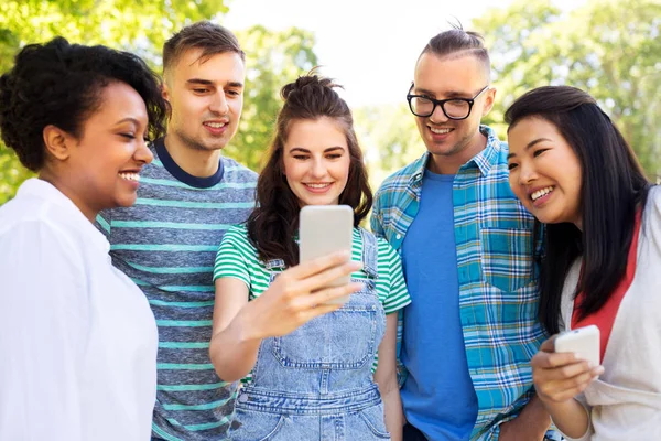 Glückliche Freunde mit Smartphone im Sommerpark — Stockfoto