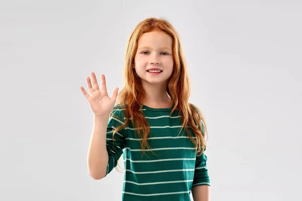 Sorrindo menina de cabelos vermelhos acenando mão — Fotografia de Stock