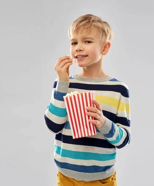 Liten pojke äter popcorn från papper hink — Stockfoto