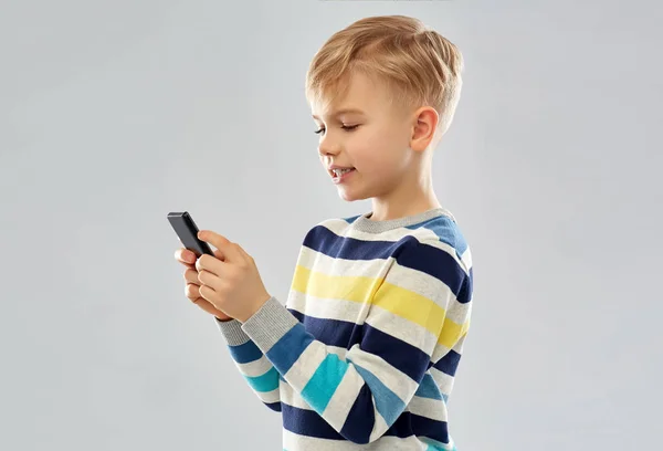 Мальчик в полосатом свитере с помощью смартфона — стоковое фото