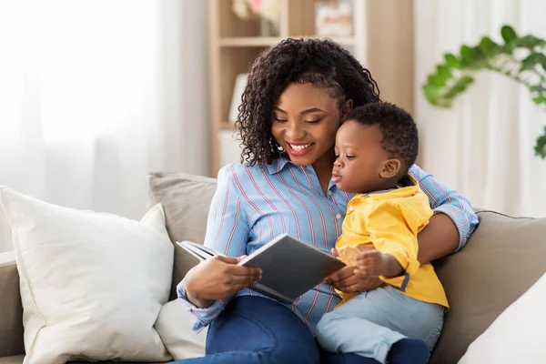 Afro-Amerikaanse moeder met boek en baby thuis — Stockfoto