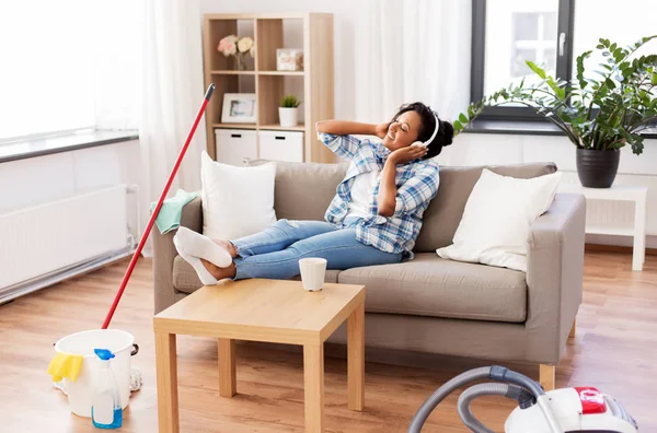 Mujer en auriculares descansando después de la limpieza del hogar — Foto de Stock