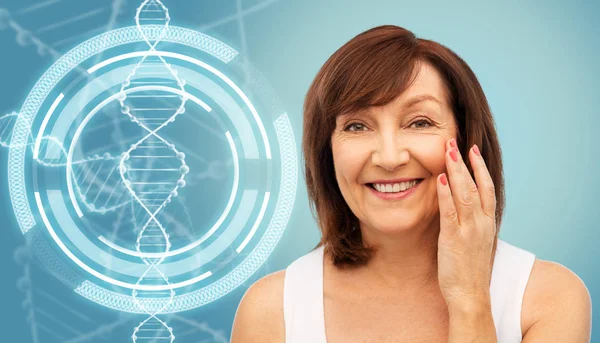 Старша жінка торкається її обличчя над молекулою ДНК — стокове фото