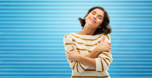 Happy woman in striped pullover hugging herself — Stock Photo, Image