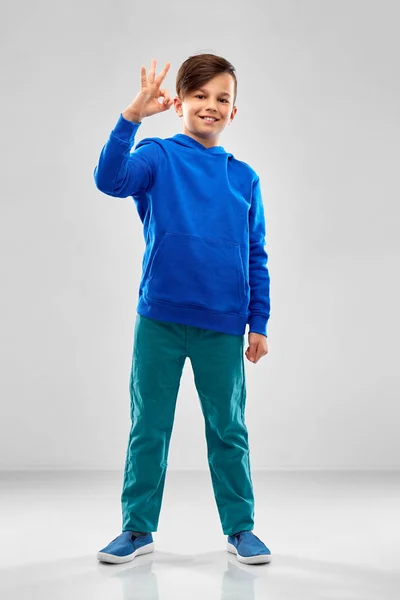 Menino de capuz azul mostrando ok sinal de mão — Fotografia de Stock