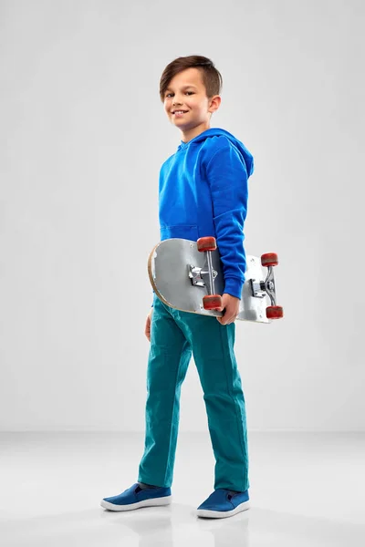 Lachende jongen in blauwe hoodie met skateboard — Stockfoto