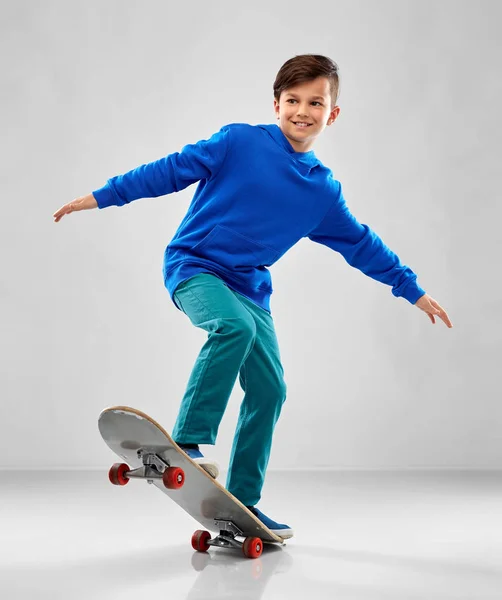 Lachende jongen in blauwe hoodie met skateboard — Stockfoto