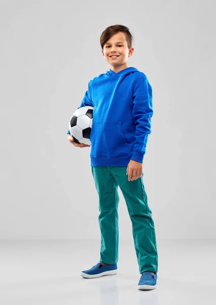 Улыбающийся мальчик в синей толстовке с футбольным мячом — стоковое фото