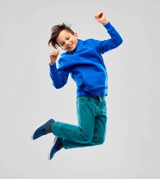 Retrato de niño sonriente con capucha azul saltando —  Fotos de Stock