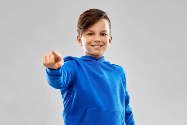 Lachende jongen in blauwe hoodier wijzend vinger — Stockfoto