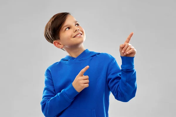 Gelukkige jongen in blauwe hoodie wijzende vingers naar boven — Stockfoto