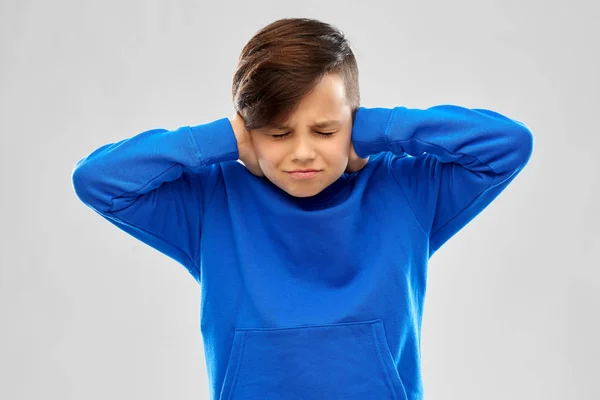 Vystresovaný chlapec v modrém svetru při zavírání uší rukama — Stock fotografie