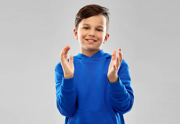 Retrato de menino sorridente com capuz azul aplaudindo — Fotografia de Stock