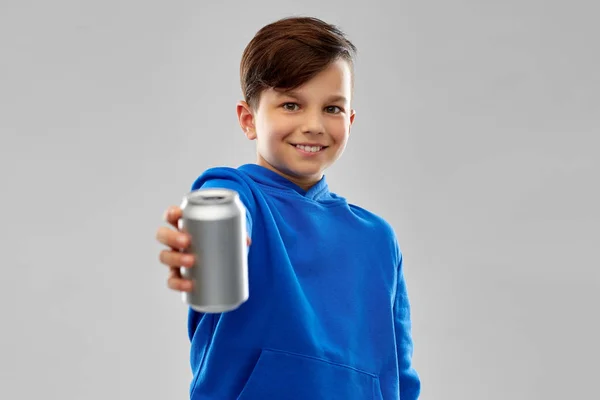 Menino sorridente em azul capuz segurando pode beber — Fotografia de Stock