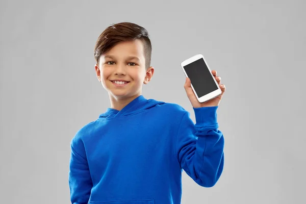 Усміхнений хлопчик у блакитному светрі, що показує смартфон — стокове фото