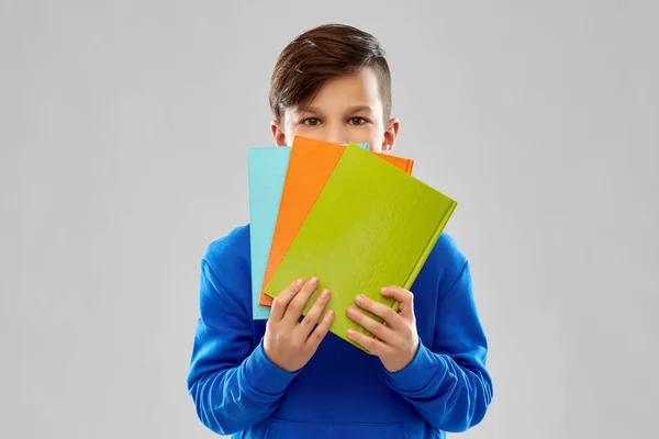 Tímido estudante menino escondido atrás de livros — Fotografia de Stock