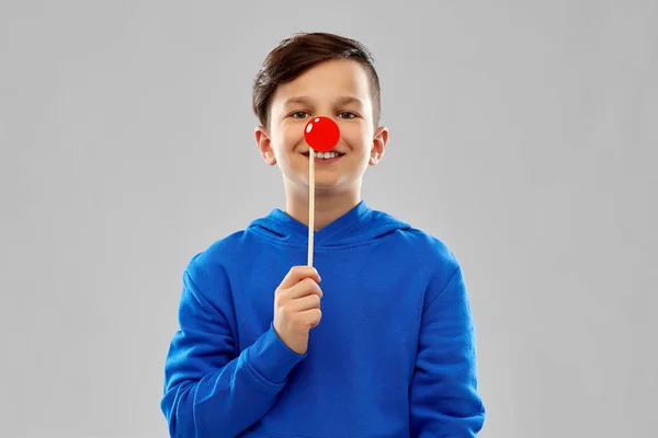Улыбающийся мальчик в синей толстовке с красным клоунским носом — стоковое фото