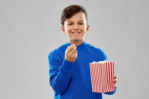 Feliz niño sonriente con capucha azul comiendo palomitas de maíz — Foto de Stock