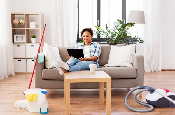 Mujer con la PC del comprimido que descansa después de la limpieza casera — Foto de Stock