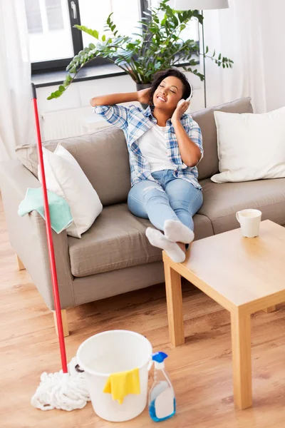 Mulher em fones de ouvido descansando após a limpeza em casa — Fotografia de Stock