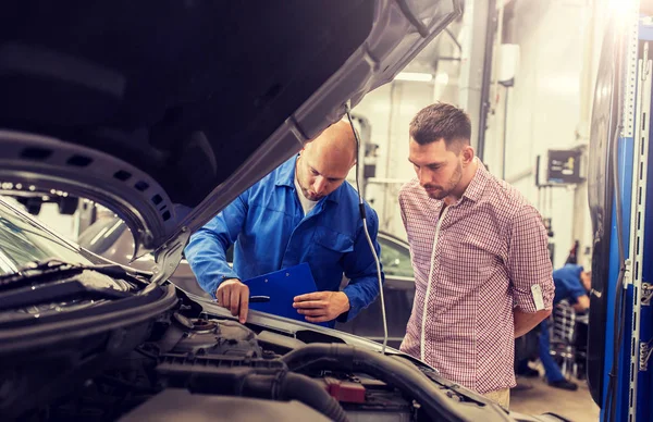 Automechaniker mit Klemmbrett und Mann im Autohaus — Stockfoto