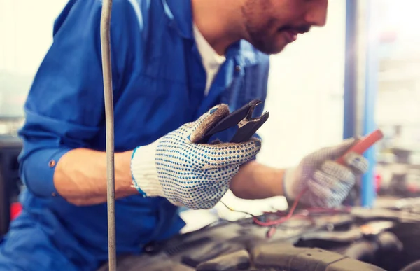 Auto mechanic man with cleats charging battery — Stock Photo, Image