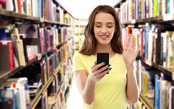 Uczeń o rozmowę wideo na smartfonie w bibliotece — Zdjęcie stockowe