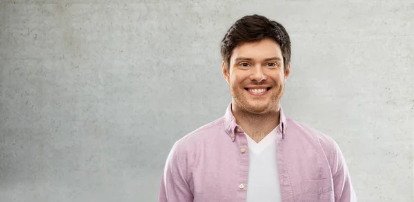 Sonriente joven hombre sobre gris muro de hormigón —  Fotos de Stock