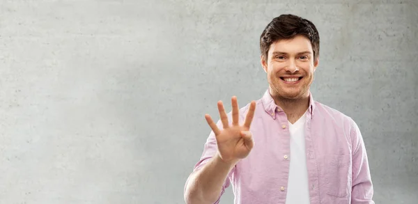 Άνθρωπος που δείχνει τέσσερα δάχτυλα πάνω από γκρι τσιμεντένιο τοίχο — Φωτογραφία Αρχείου