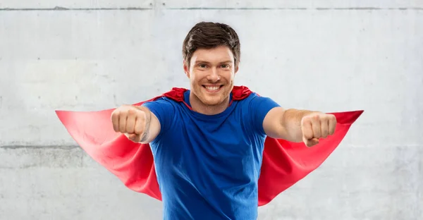 Homem em capa de super-herói vermelho sobre fundo de concreto — Fotografia de Stock
