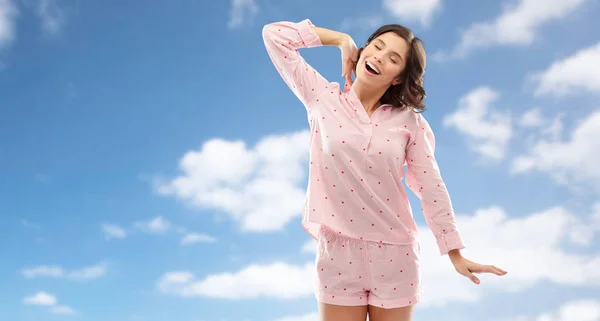 Feliz jovem mulher no pijama que se estende sobre o céu — Fotografia de Stock