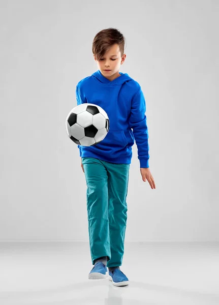 Sorrindo menino com capuz azul jogando bola de futebol — Fotografia de Stock