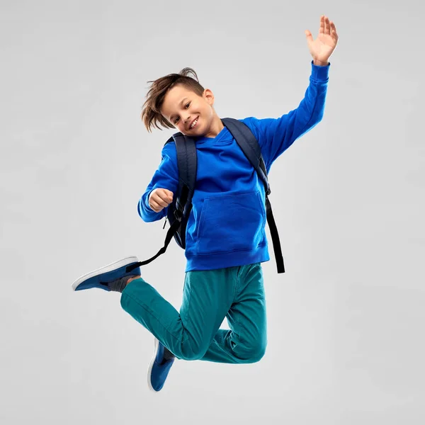 Happy smiling student boy with school bag jumping — Stock Photo, Image