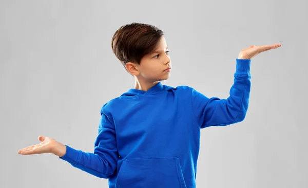 Boy in blue holding something on empty hands — Stock Photo, Image